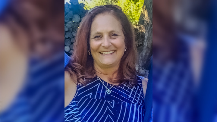 A smiling woman in a blue dress.